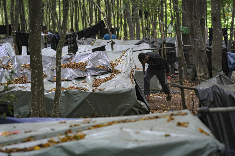 A migrant man prepares to enter an improvised tent in a makeshift camp in a wood outside Velika Kladusa, Bosnia, Saturday, Sept. 26, 2020.(AP Photo/Kemal Softic)