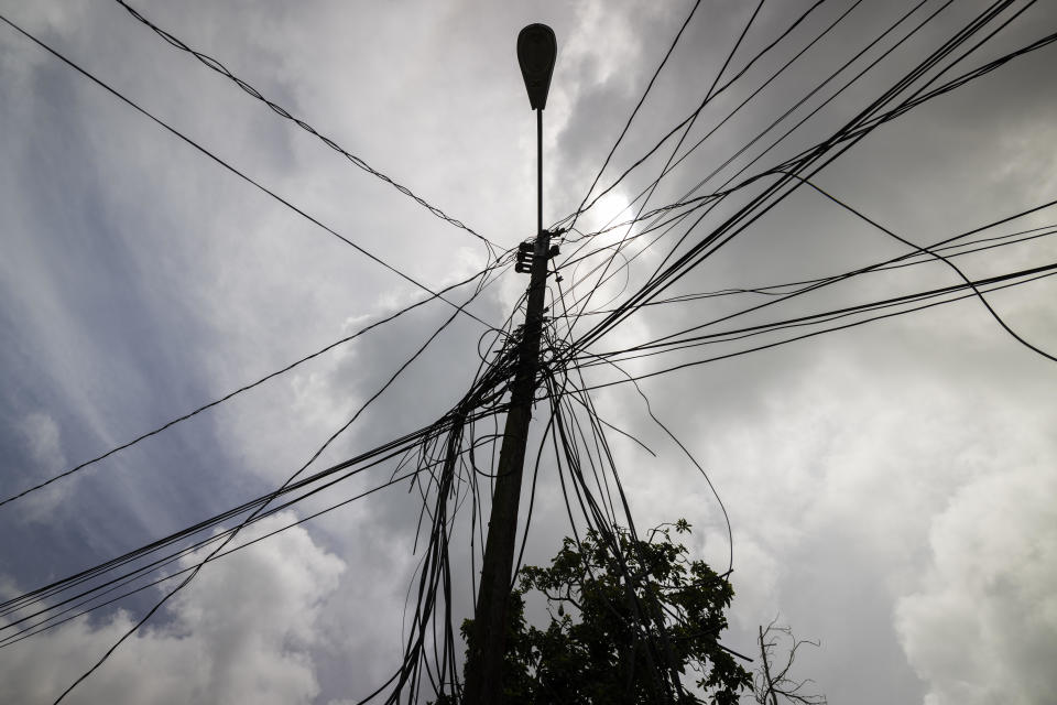 A utility pole with loose cables towers over the home of Jetsabel Osorio in Loiza, Puerto Rico, Thursday, Sept. 15, 2022. Nearly five years have gone by since Hurricane Maria struck Puerto Rico. Crews only recently started to rebuild the power grid with more than $9 billion of federal funds as island-wide blackouts and daily power outages persist. (AP Photo/Alejandro Granadillo)