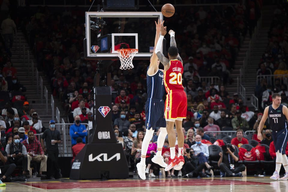 Atlanta Hawks John Collins (20) shoots a three pointer over Dallas Mavericks Kristaps Porzingis (6) during the second half of an NBA basketball game Thursday, Oct. 21, 2021, in Atlanta. (AP Photo/Hakim Wright Sr.)