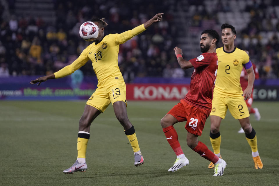 Malaysia's Mohamadou Sumareh, left, goes for the ball during the Asian Cup Group E soccer match between Malaysia and Bahrain at Jassim bin Hamad Stadium in Doha, Qatar, Saturday, Jan. 20, 2024. (AP Photo/Thanassis Stavrakis)