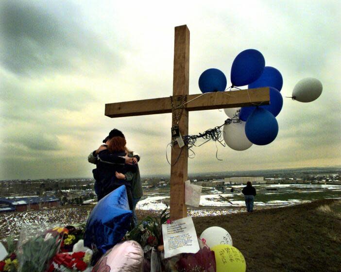 FILE - In this April 24, 1999, file photo, students embrace each other at a makeshift memorial for their slain classmates at Columbine High School on a hilltop overlooking the school in Littleton, Colo. Twelve students and one teacher were killed in a murderous rampage at the school on April 20, 1999, by two students who killed themselves in the aftermath. (AP Photo/Bebeto Matthews, File)