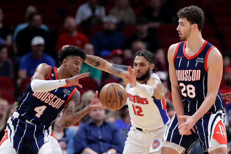 Detroit Pistons forward Isaiah Livers (12) reaches to knock away a pass intended for Houston Rockets guard Jalen Green (4) as Rockets center Alperen Sengun, right, screens during the first half at Toyota Center in Houston on Friday, March 31, 2023.