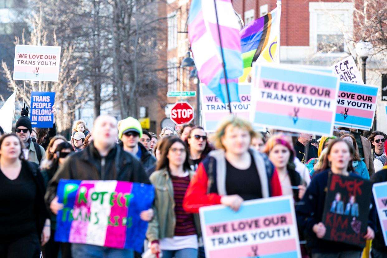 People hold sings from the United Action for Youth reading "We love our trans youth" during a Trans Day of Visibility event, Saturday, April 1, 2023, in Iowa City, Iowa.