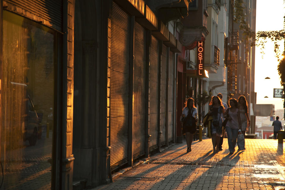 A group of women walking past a hostel at sunset.