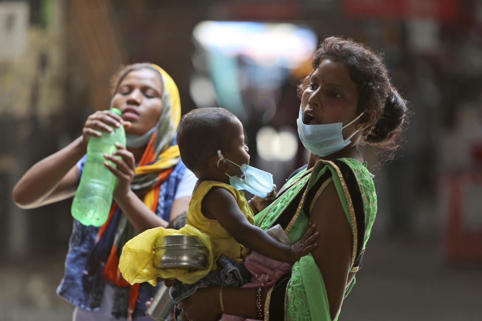 A woman carries a child and waits for transportation at a bus station in Jammu, India, Friday, Sept. 11, 2020. By early May, 6.4 million people in India were likely infected by the coronavirus, said a study released Thursday, Sept. 10, by Indian scientists from the Indian Council of Medical Research, India’s apex medical research body and published in their in-house medical journal. At the time, India had detected around 35,000 cases and over a thousand deaths. But the results of India’s first nationwide study of prevailing infections in the country found that for every confirmed case that detected in May, authorities were missing between 82 and 130 infections. The study tested 28,000 people for proteins produced in response to the virus in the villages and towns across 70 districts in 21 Indian states between May 11 to June 14. (AP Photo/Channi Anand)