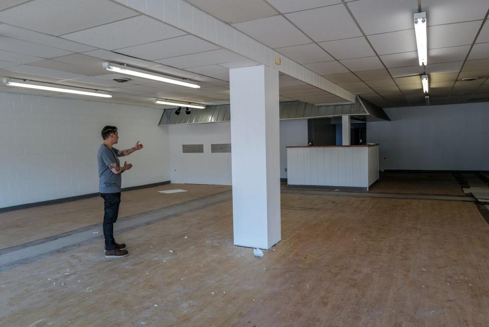 Megan Shannon shows where a wall will divide the woodworking workshop area from the planned retail space in her new location at 507 E. Shiawassee Street in Lansing's Stadium District Wednesday, July 19, 2023.