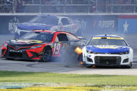 Chase Elliott (9) has his tire catch fire as Martin Truex Jr. (19) and Corey LaJoie (7) drive past during the NASCAR Cup Series auto race at Texas Motor Speedway in Fort Worth, Texas, Sunday, Sept. 25, 2022. (AP Photo/Larry Papke)