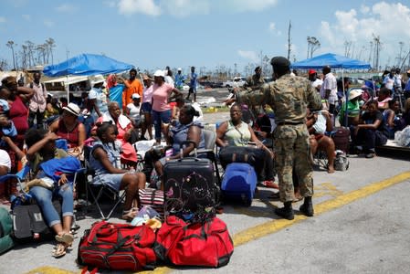 A soldier controls the crowd as people wait in line to get in a airplane during an evacuation operation after Hurricane Dorian hit the Abaco Islands in Treasure Cay