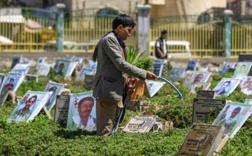 A Yemeni boy waters plants and cleans tombstones in a cemetery in the capital Sanaa on March 25, 2019
