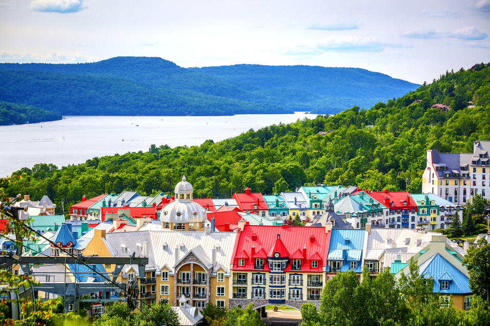 Scenic view of Mont-Tremblant village with colorful rooftops, nestled among lush green hills and near a serene lake