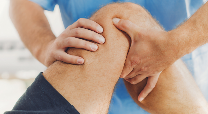 Physiotherapist doing healing treatment on patient leg. Therapist wearing blue uniform. Osteopathy, Chiropractic leg adjustment. Orthopedic therapy. ATIP stck.