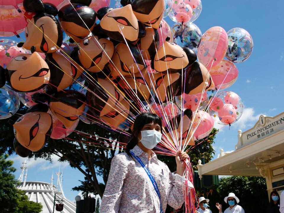 An employee holds balloons at the Disneyland theme park after it reopened following a shutdown due to the coronavirus disease (COVID-19) in Hong Kong, China June 18, 2020. REUTERS/Tyrone Siu