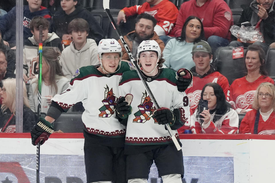 Arizona Coyotes center Logan Cooley, right, is greeted by defenseman Travis Dermott (33) after scoring on Detroit Red Wings goaltender Alex Lyon during the first period of an NHL hockey game, Thursday, March 14, 2024, in Detroit. (AP Photo/Carlos Osorio)