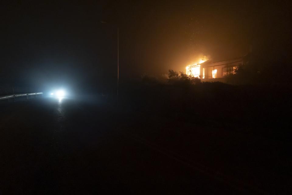 A house is on fire in Rovies village on the island of Evia, about 160 kilometers (100 miles) north of Athens, Greece, late Wednesday, Aug. 4, 2021. Greece evacuated people in boats from an island beach Wednesday amid heavy smoke from a nearby wildfire and fire crews fought elsewhere to keep flames away from the birthplace of the ancient Olympic Games as the country sweltered under a record heat wave. (AP Photo/Thodoris Nikolaou)