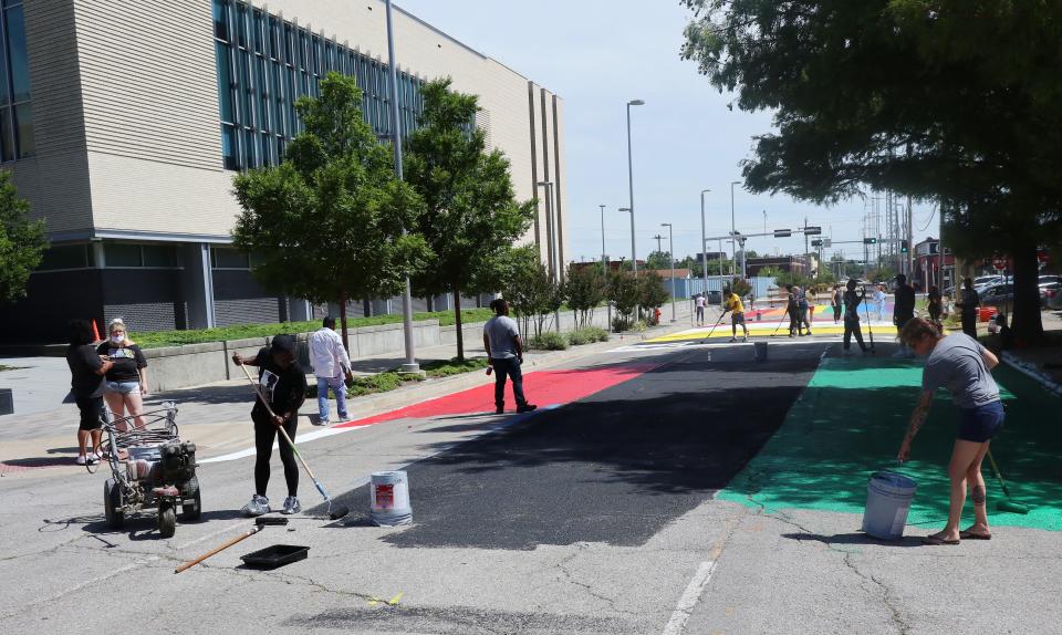 People work June 23, 2020, to paint portions of Shartel Avenue, next to the Oklahoma City police headquarters.