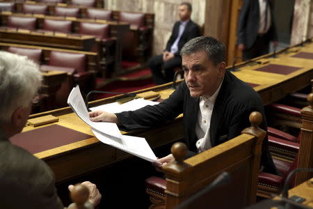 Greek Finance Minister Euclid Tsakalotos holds a draft of a reforms bill as he talks with Justice Minister Nikos Paraskevopoulos (L) before a parliamentary session in Athens, Greece July 22, 2015. REUTERS/Yiannis Kourtoglou