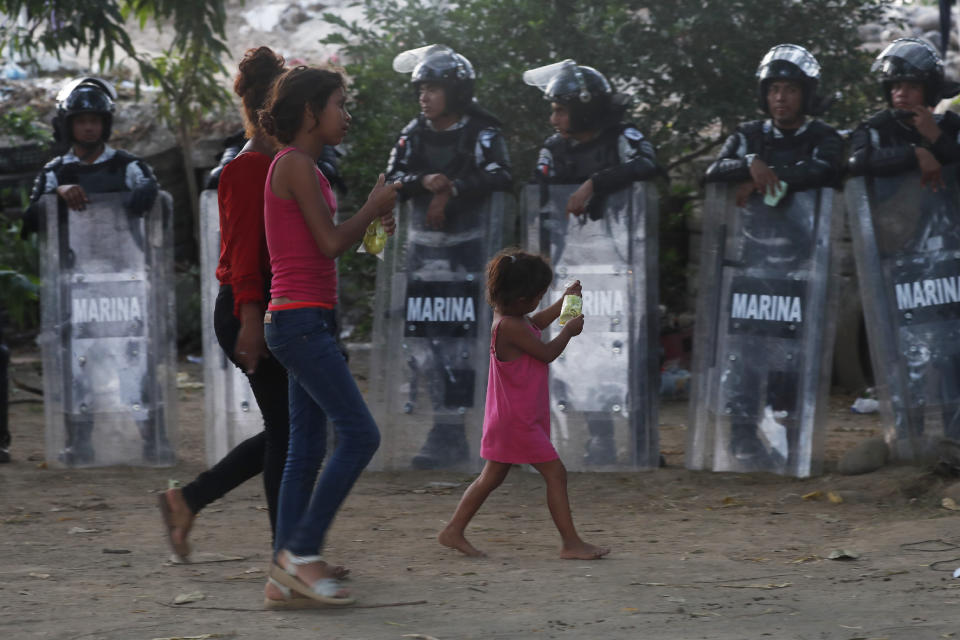 Migrantes centroamericanas pasan junto a una línea de guardias nacionales mexicanos en la frontera con Guatemala, cerca de Ciudad Hidalgo, México, el lunes 20 de enero de 2020. (AP Foto/Marco Ugarte)