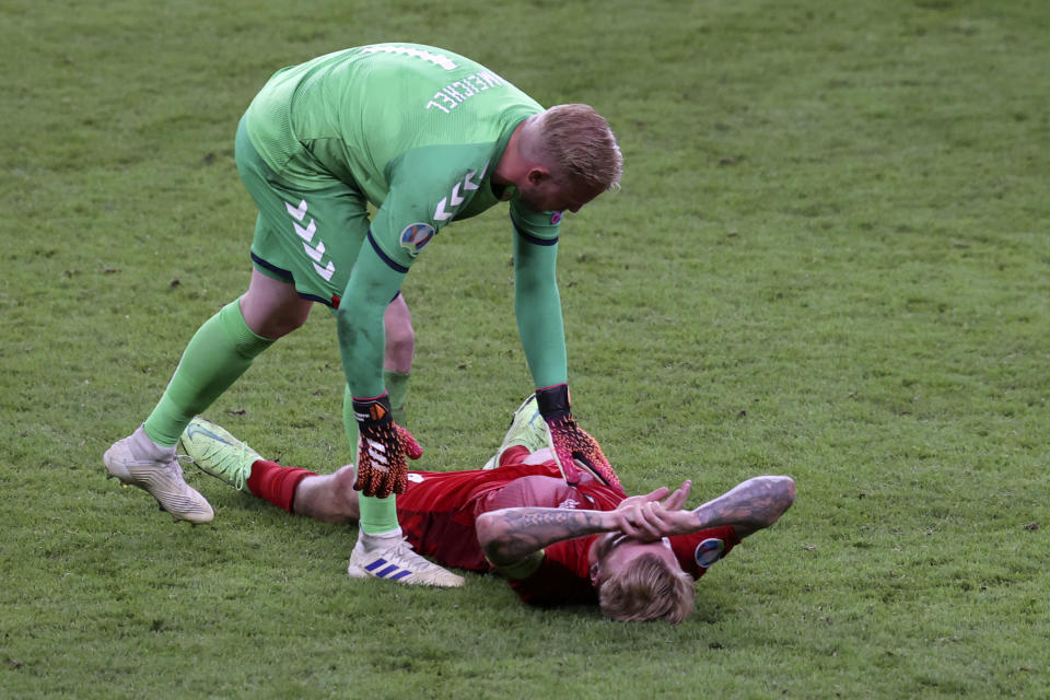 Kasper Schmeichel, arquero de Dinamarca, consuela a su compañero Simon Kjaer, tras la derrota ante Inglaterra en las semifinales de la Eurocopa, el miércoles 7 de julio de 2021 (Catherine Ivill/Pool Photo via AP)