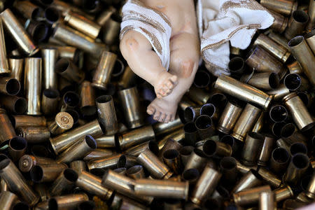 A statue of the baby Jesus on a bed of bullet shells is seen in a Nativity scene outside the Basilica of St Francis in Assisi, Italy, December 21, 2017. The 445 shells represent the number of priests, nuns, monks and religious teachers killed for their faith since 2000. Picture taken December 21, 2017. REUTERS/Alessandro Bianchi