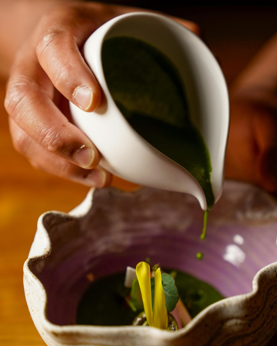 Chef Aaron Verzosa pours a wild nettle laing sauce to complete the Anak ni Bet, his version of pinakbet, at Filipino American restaurant Archipelago, Wednesday, May 24, 2023, in Seattle. Verzosa is nominated for a 2023 James Beard Award in the Best Chef: Northwest and Pacific category. (AP Photo/Lindsey Wasson)