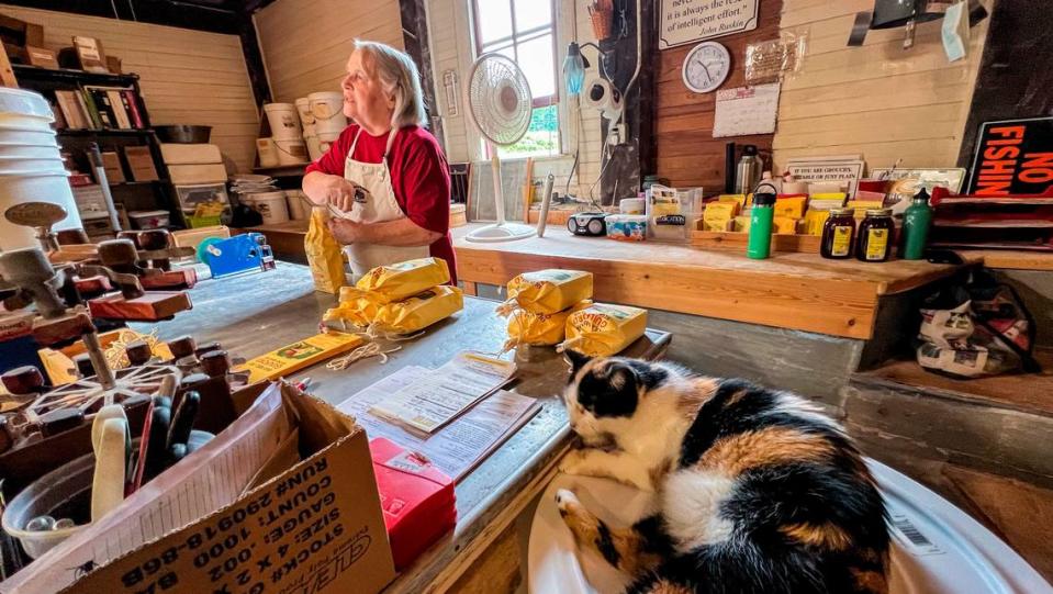 Miller Annie Perdue bags ground grain as her cat ‘Millie’ sleeps nearby at the Old Mill of Guilford, built in 1767. Travis Long/tlong@newsobserver.com