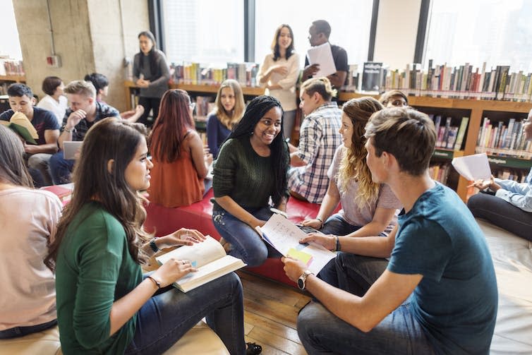 A group of university students talk with each other about their coursework.