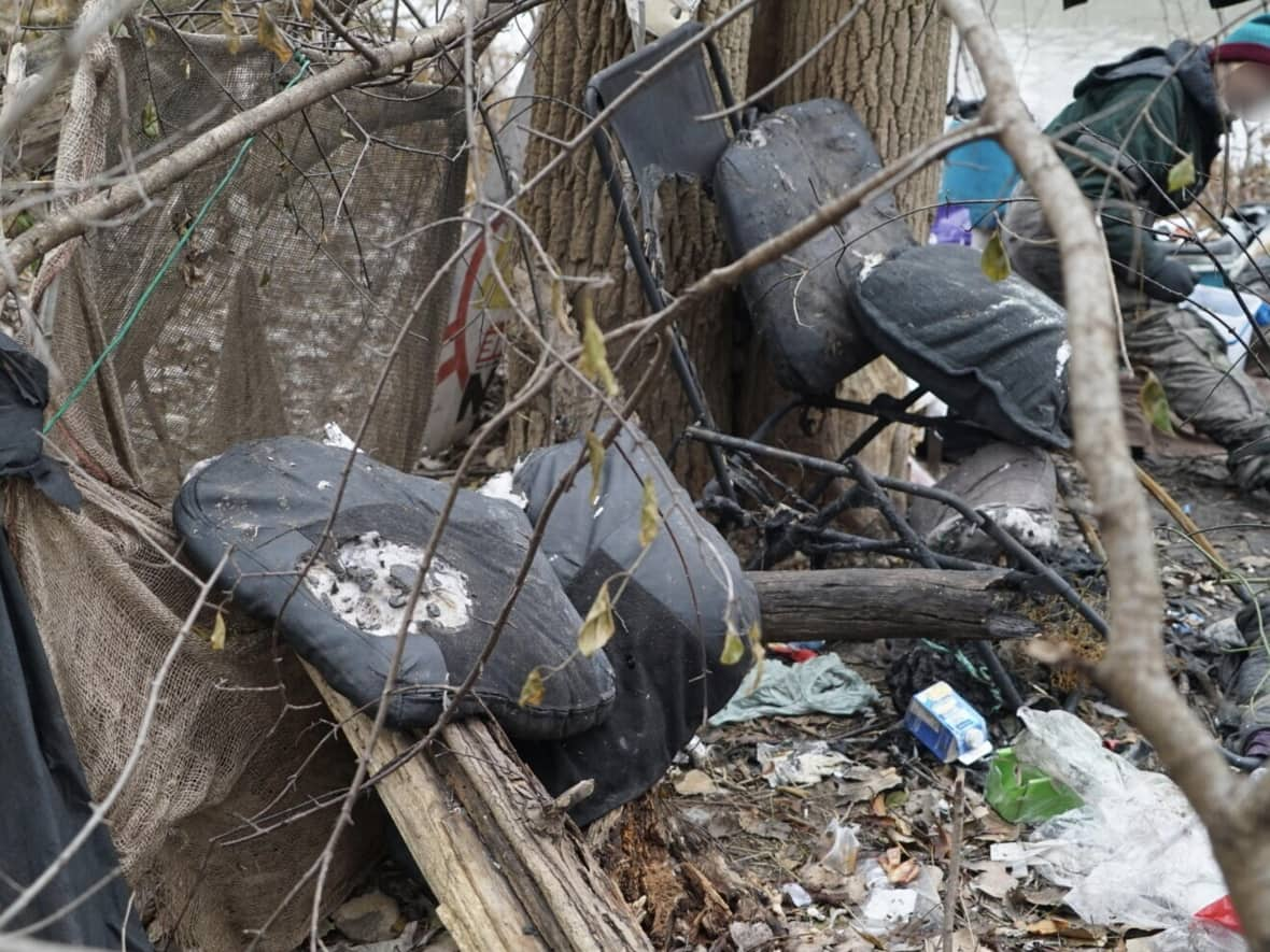 A homeless man sifts through what's left of his possessions after a fire destroyed his encampment in downtown London, Ont. It's a scene that's becoming more common, increasing the likelihood of injury and keeping firefighters on their toes.  (Colin Butler/CBC News - image credit)