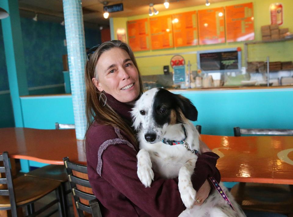 Julie Burke holds Juno, a rescued dog from Nicaragua, at Las Olas Taqueria in Hampton Tuesday, Jan. 24, 2023. She and her husband, Matt, co-owners of Las Olas in Hampton, Exeter and Wells, Maine, live part-time in Nicaragua where they have started an animal shelter organization.