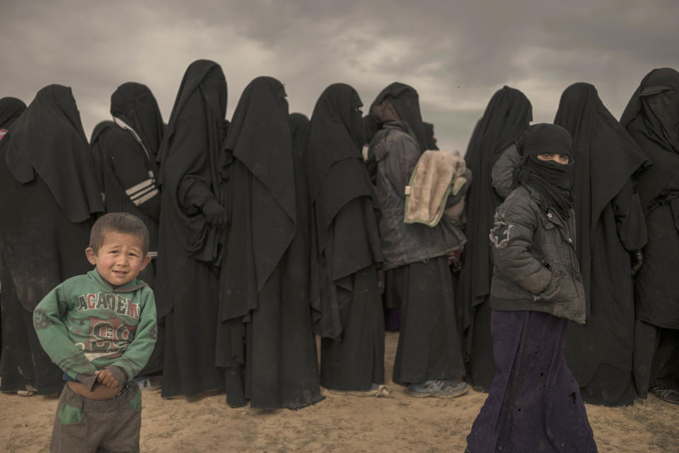 In this Wednesday, March 6, 2019, photo, women and children stand in line at a reception area for people evacuated from the last shred of territory held by Islamic State militants, outside Baghouz, Syria. (AP Photo/Gabriel Chaim)