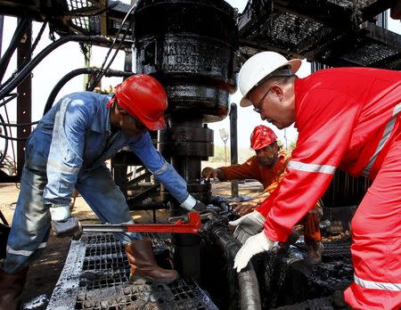 Men work at an oil pump in Lagunillas, Ciudad Ojeda, in the state of Zulia, Venezuela, March 20, 2015. REUTERS/Isaac Urrutia