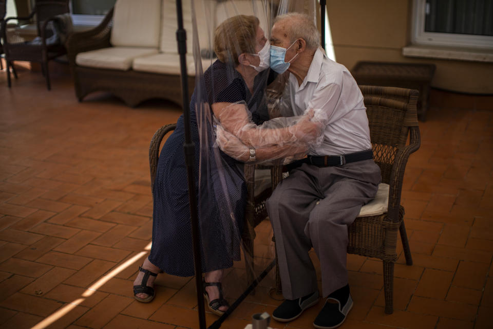 Agustina Canamero (izq), de 81 años, y Pascual Pérez, de 84, se besan a través de un panel de plástico para evitar pasarse el coronavairus en una residencia de ancianos de Barcelona el 22 de junio del 2020. (AP Photo/Emilio Morenatti)