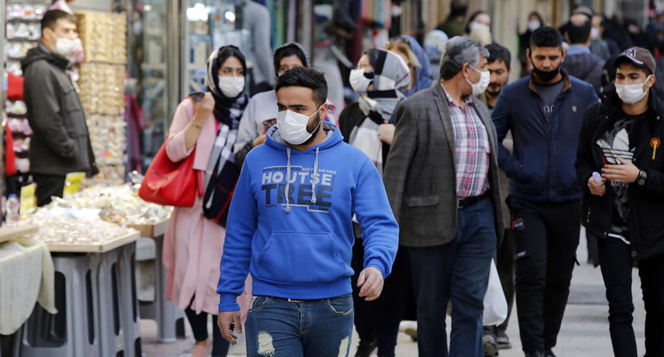 Several people are seen wearing face masks on a street in Iran.