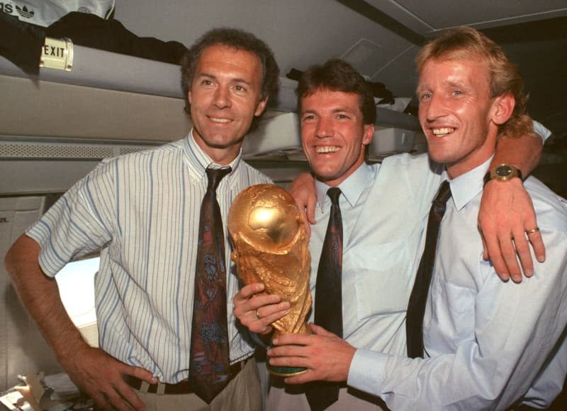 Former DFB team manager Franz Beckenbauer (L), captain and midfielder Lothar Matthaeus (C) and defender Andreas Brehme present the World Cup trophy. Wolfgang Eilmes/dpa