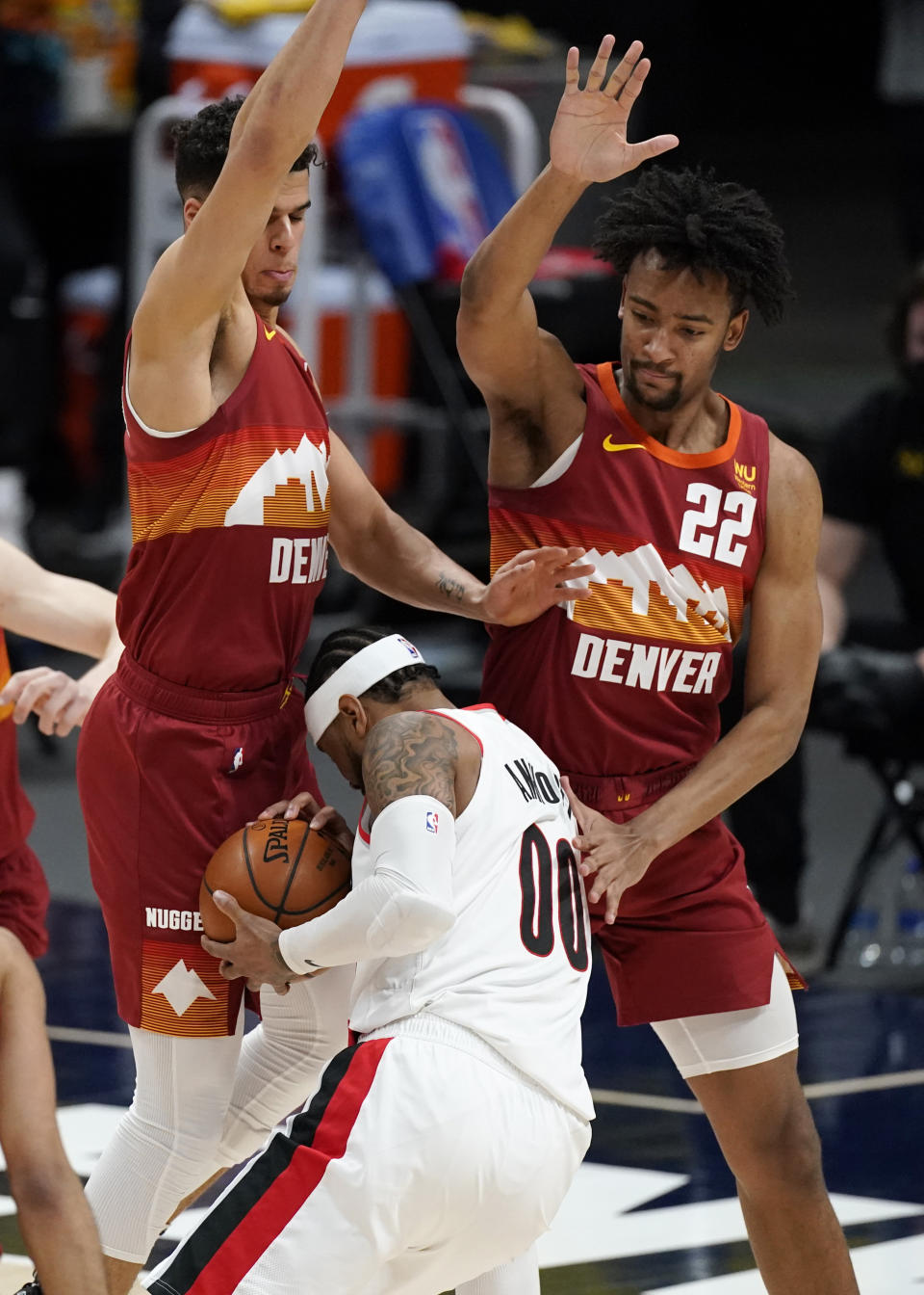 Portland Trail Blazers forward Carmelo Anthony, center, is fouled as he drives the lane as Denver Nuggets forwards Michael Porter Jr., back left, and Zeke Nnaji defend in the first half of an NBA basketball game on Tuesday, Feb. 23, 2021, in Denver. (AP Photo/David Zalubowski)
