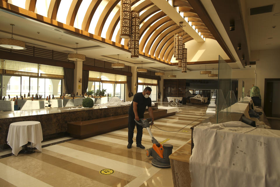 A hotel employee wearing a protective face mask cleans the floor of the reception in Antalya, southern Turkey, Saturday, June 19, 2021. Hotels in Turkey's Antalya region, a destination beloved by holidaymakers, are preparing to finally resume operations as they expect the return of international tourists after months of setbacks caused by the pandemic that halted travel. (AP Photo/Emrah Gurel)