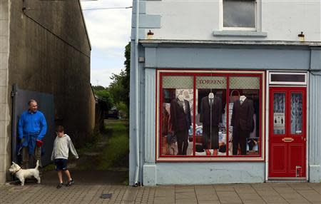 People stand next to an empty building which has been covered with artwork to make it look more appealing, in the village of Bushmills on the Causeway Coast August 19, 2013. REUTERS/Cathal McNaughton