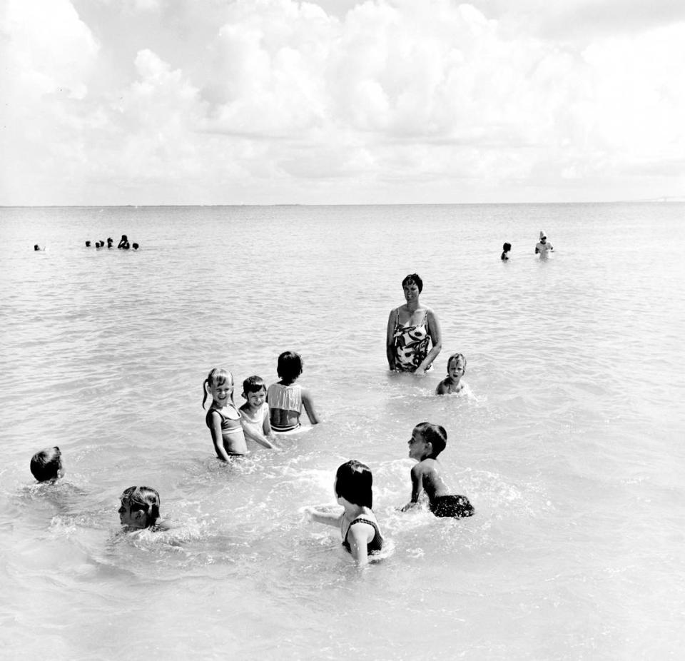 Multiple children playing and swimming at the Manatee Public Beach.