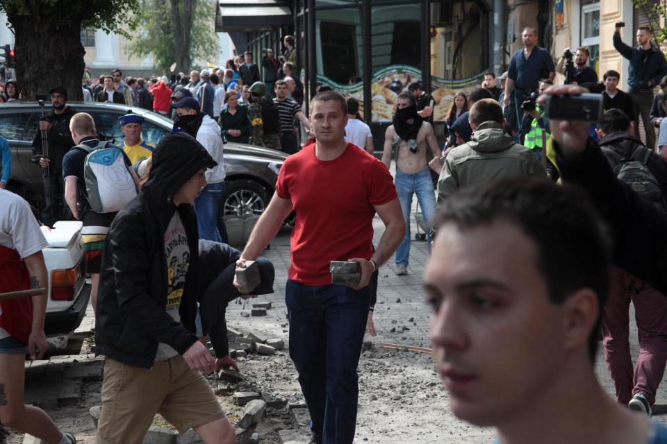 A Ukrainian government supporter carries stones during a clash with pro-Russians in the Black Sea port of Odessa, Ukraine, Friday, May 2, 2014. A clash broke out late Friday between pro-Russians and government supporters in Odessa, on the Black Sea coast some 550 kilometers (330 miles) from the turmoil in the east. Odessa had remained largely untroubled by unrest since the February toppling of pro-Russia President Viktor Yanukovych, which ignited tensions in the east. (AP Photo/Sergei Poliakov)