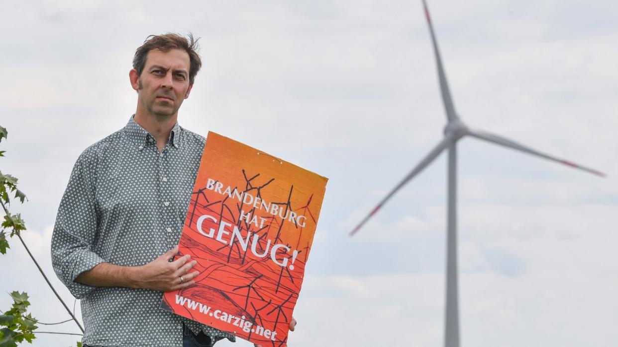 Eigenheimbesitzer Stefan Hellert auf seinem Grundstück. In rund 1500 Metern Entfernung dreht sich der Rotor einer Windenergieanlage.