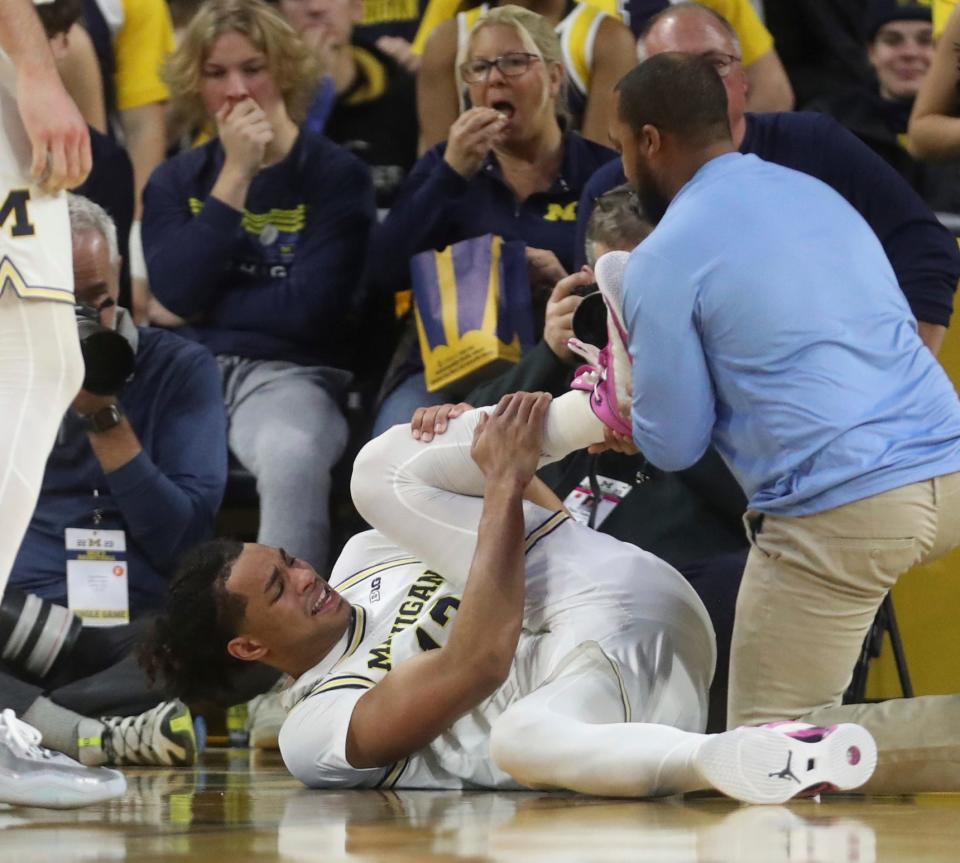 Michigan guard Jett Howard grabs his left leg while a team trainer attends to him during the first half of U-M's 60-56 win on Sunday, Jan. 22, 2023, at Crisler Center.