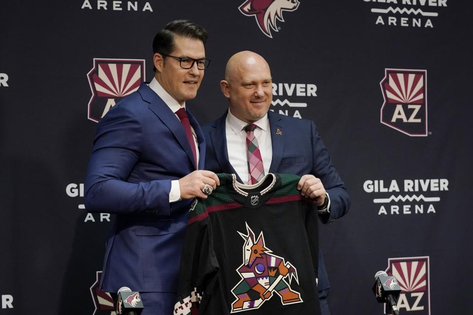 Arizona Coyotes hockey team General Manager Bill Armstrong, left, poses with new head coach Andre Tourigny, right, as the two hold up a jersey during a news conference at Gila River Arena Thursday, July 1, 2021, in Glendale, Ariz. (AP Photo/Ross D. Franklin)