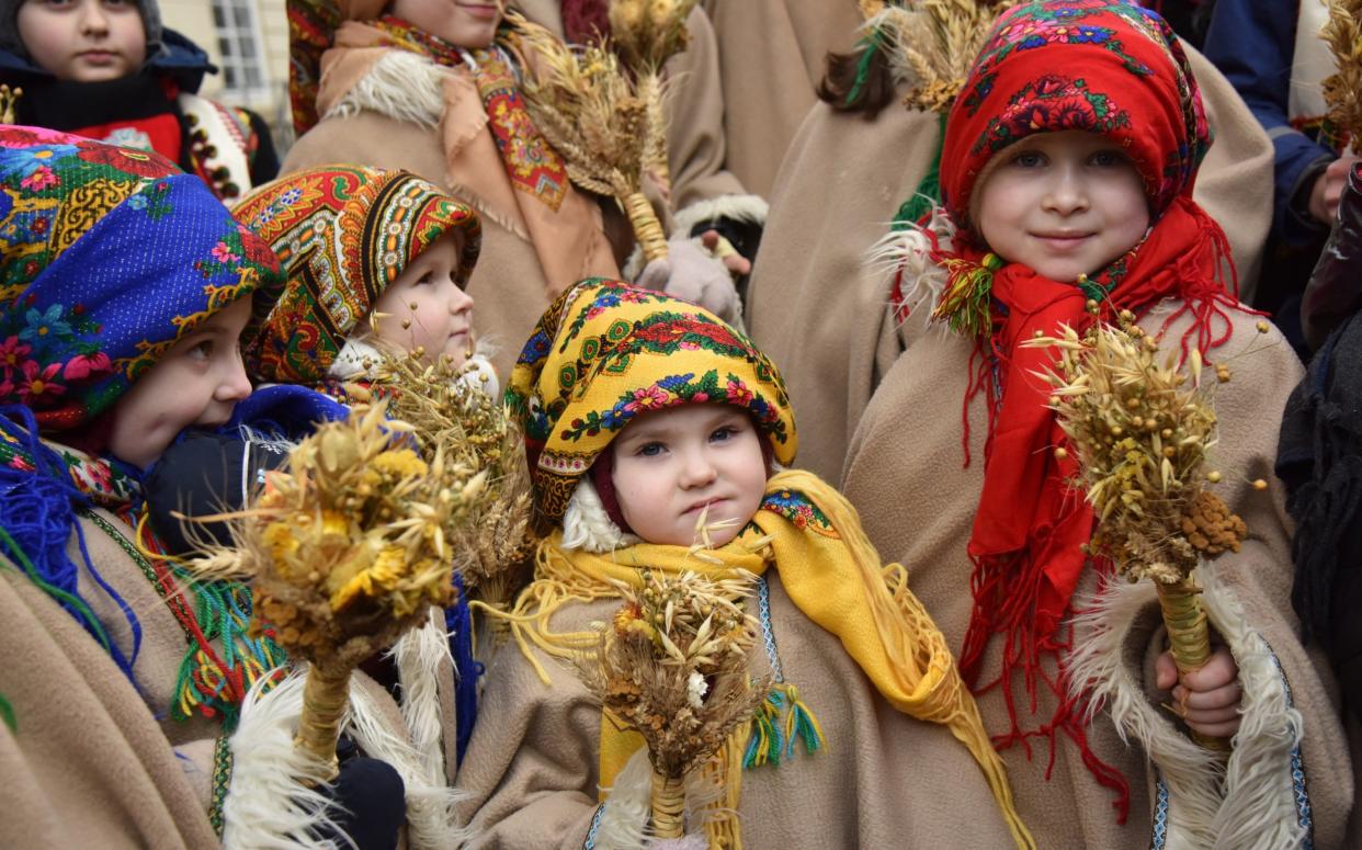 Children hold sheaves of wheat called didukh on a Christmas parade in Lviv