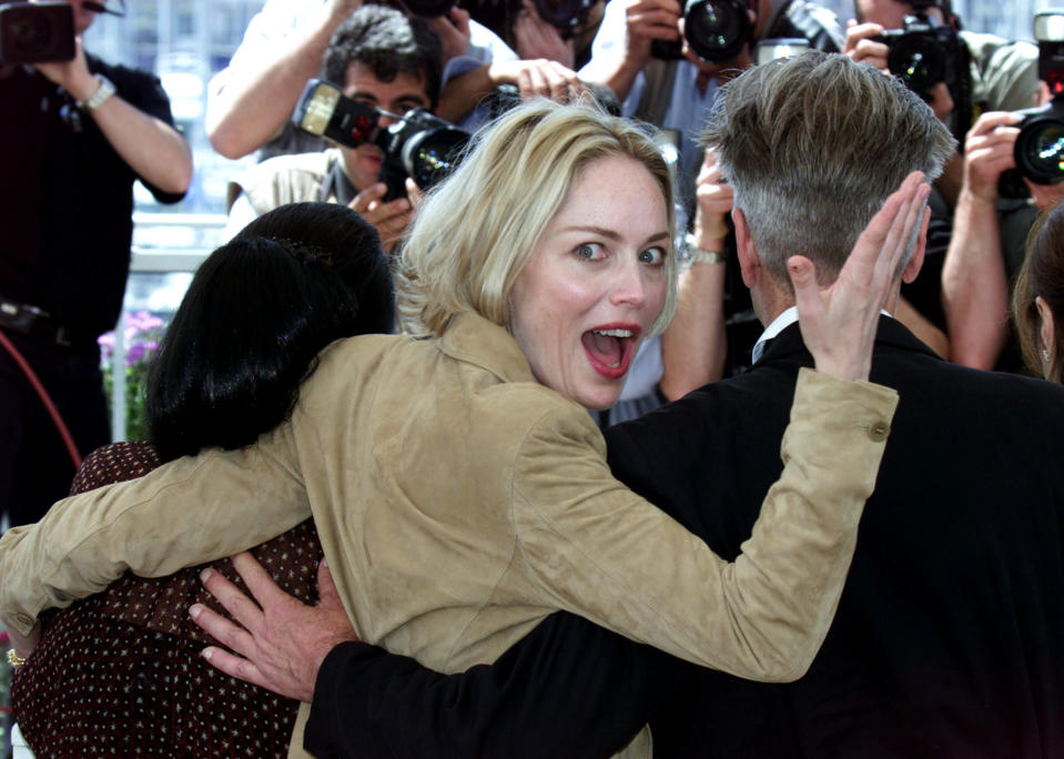 U.S. actress Sharon Stone (C) looks back at photographers as she stands  next to U.S. director David Lynch (R), President of the Jury at the  55th International Cannes Film Festival, and Indonesian actress  Christine Hakim (L), during a photo call in Cannes May 15, 2002.  REUTERS/Jean Paul Pelissier    VK