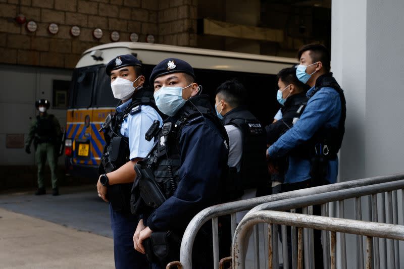 Armed police stand guard as they escort a prison van that is believed to carry media mogul Jimmy Lai, founder of Apple Daily, to the High Court in Hong Kong