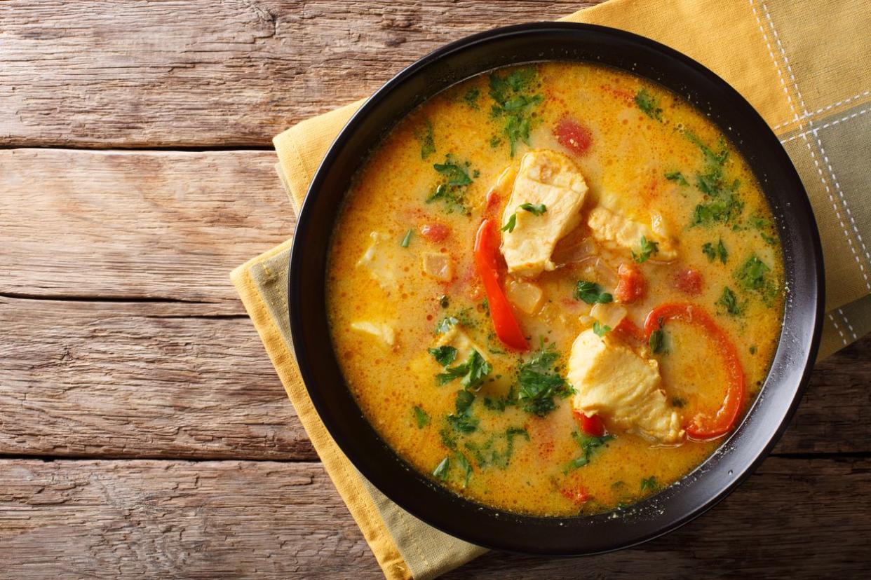 Brazilian food: Moqueca Baiana of fish and bell peppers in spicy coconut sauce close-up on a plate on a table