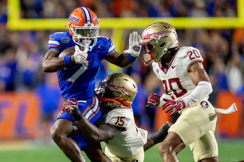 Florida Gators running back Trevor Etienne (7) rushes with the ball while Florida State Seminoles linebacker Tatum Bethune (15) and Florida State Seminoles defensive back Azareye’h Thomas (20) attempt to tackle during the first half at Steve Spurrier Field at Ben Hill Griffin Stadium in Gainesville, FL on Saturday, November 25, 2023. [Matt Pendleton/Gainesville Sun]