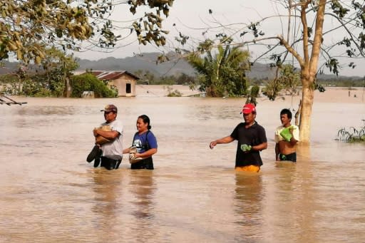 Residents wade through a highway flooded by typhoon Phanfone in Ormoc City, Leyte province