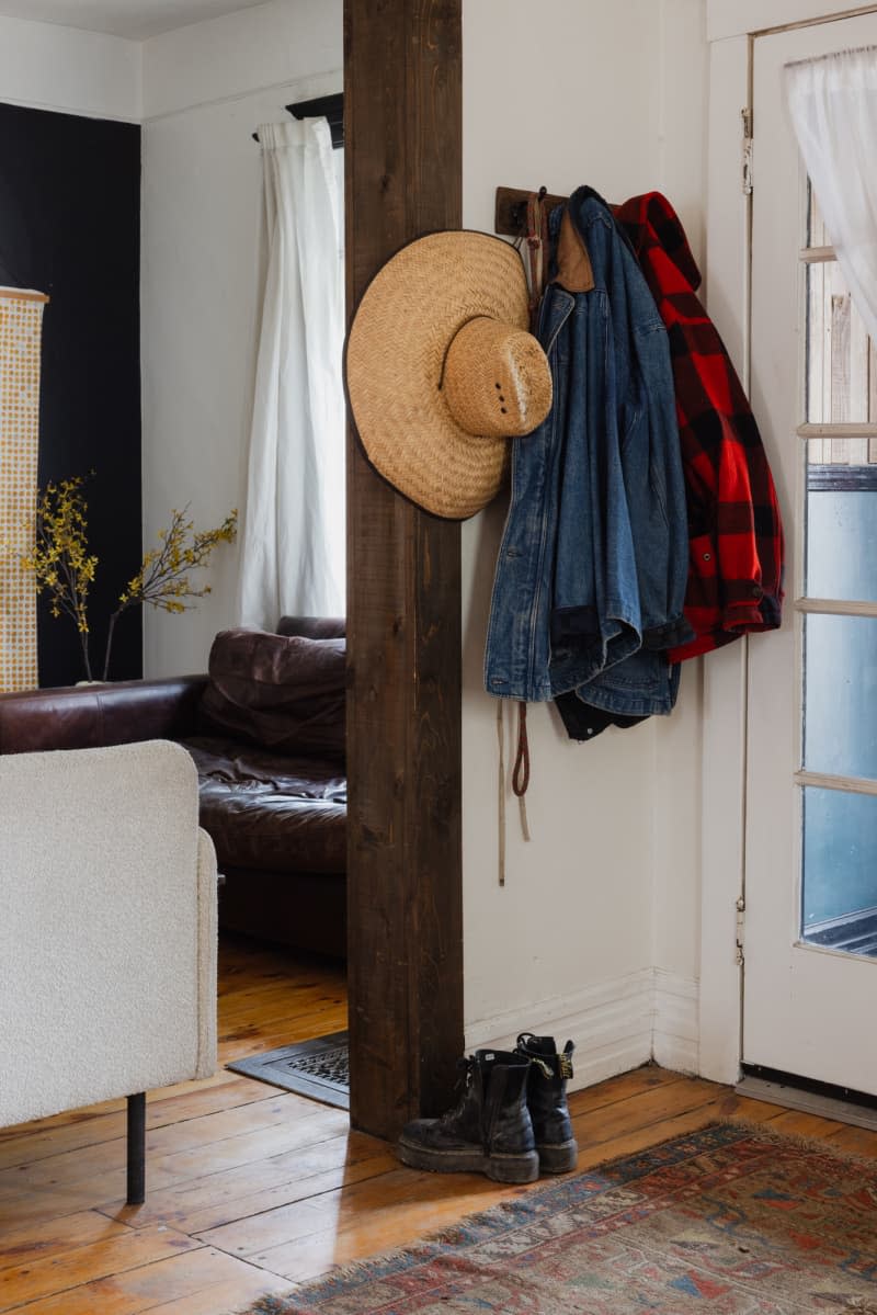 Hat and jackets hung next to door, above boots.