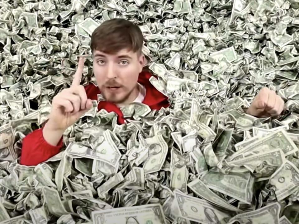 A picture of MrBeast sitting in a pile of cash.