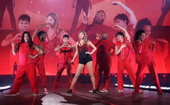 Taylor Swift performing on stage with dancers all dressed in red